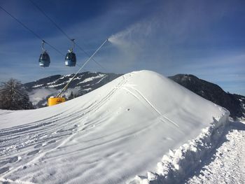 Ski lift over snow covered mountains against sky