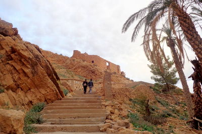 Rear view of people walking on mountain against sky