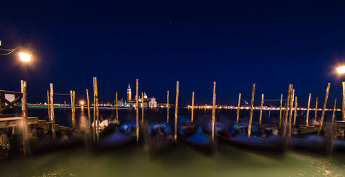 Boats moored in canal against clear sky at night