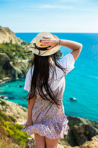 Midsection of woman standing in sea against sky