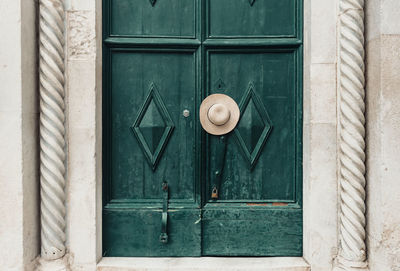 Sun hat hanging on door handle of old wooden green door