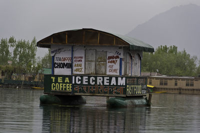 Information sign in front of river against sky