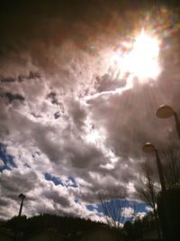 Low angle view of sun shining through clouds