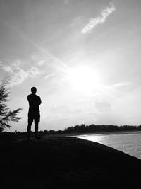 Rear view of silhouette man standing on land against sky