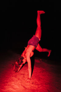 Full length of woman doing handstand at night