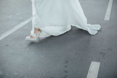 Low section of woman with high heels on road