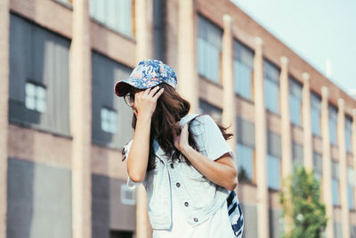Midsection of woman with umbrella against sky in city