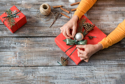 High angle view of woman tying gift during christmas on table