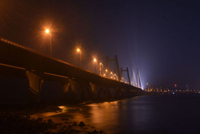 Illuminated bridge over river at night