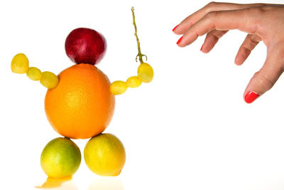 Close-up of hand holding fruits against white background