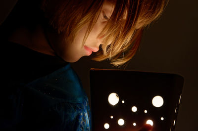 Portrait of little blonde girl in dim light looking towards a lamp