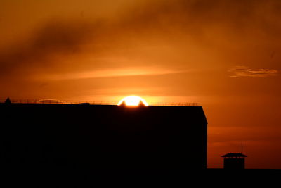 Silhouette built structure against orange sky