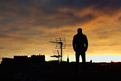 Silhouette man standing on rooftop against sky during sunrise
