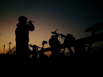 Silhouette people photographing against sky during sunset