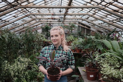 Portrait of smiling woman standing in greenhouse