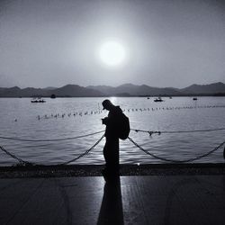 Silhouette man fishing at sea against clear sky
