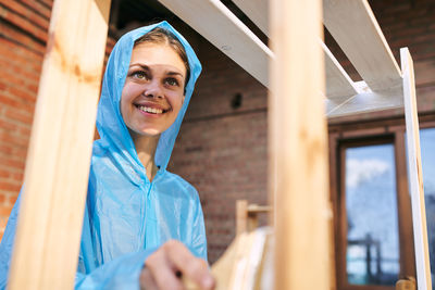 Portrait of young woman standing against building