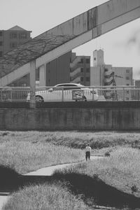 People working on field by buildings in city against sky