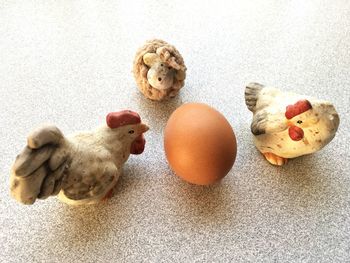 High angle view of her figurines with brown egg on table