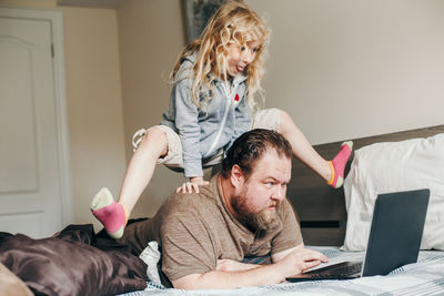 Work from home with kids children. father working on laptop in bedroom with child on his back