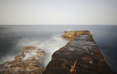 Scenic view of rocks in sea against sky