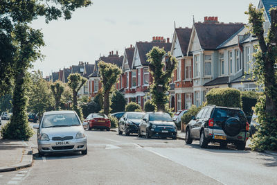 Cars on street by buildings in city against sky