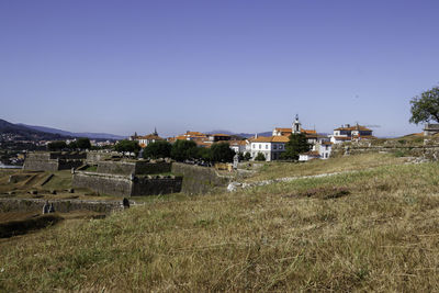 Houses on field by buildings against clear sky