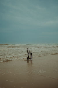 Wooden chair on beach at sunset