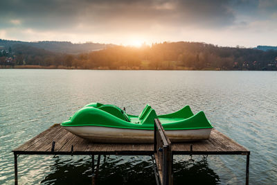Chairs in swimming pool against lake during sunset