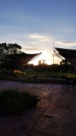 Silhouette trees by swimming pool against sky during sunset