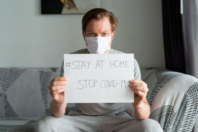 Portrait of man holding paper while sitting at home