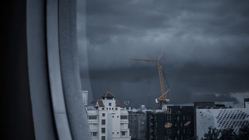 Buildings in city against storm clouds