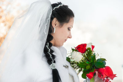 Bride holding flower bouquet while standing outdoors