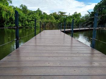 Wooden footbridge over lake against sky