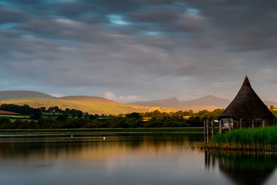 Scenic view of lake against cloudy sky during sunset