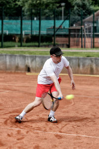 Mature man playing tennis at court