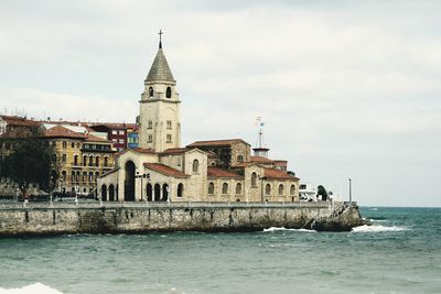 View of bell tower by sea against sky