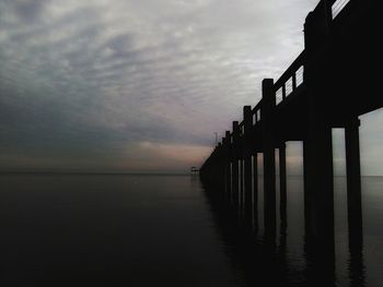Pier over sea against sky during sunset