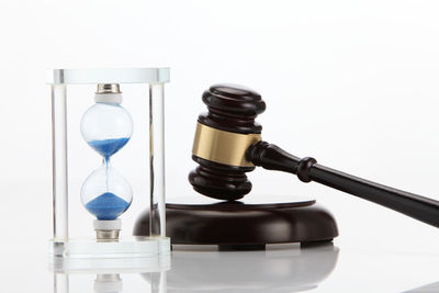 Close-up of gavel with hourglass against white background