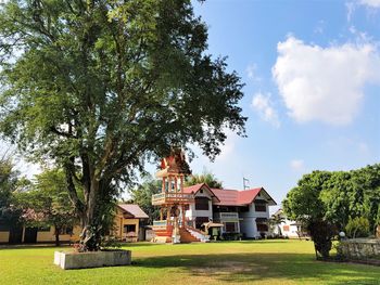 Trees and houses on field against sky