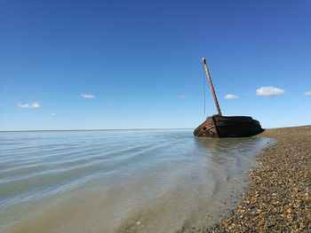 Abandoned boat at beach against sky