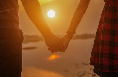 Scenic view of hands against sky during sunset