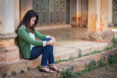Full length of woman sitting on staircase against building