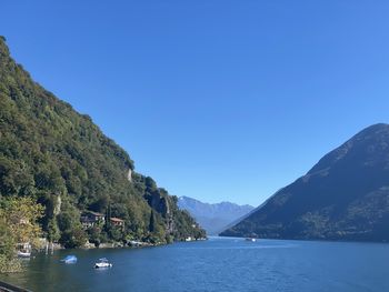 Scenic view of sea and mountains against clear blue sky