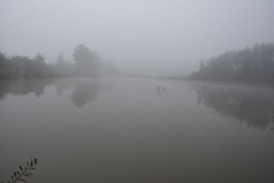 Scenic view of lake against sky at foggy weather