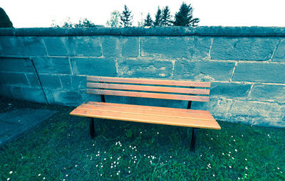 Empty bench against wall in park