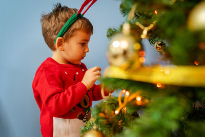 Cute boy standing by christmas tree at home