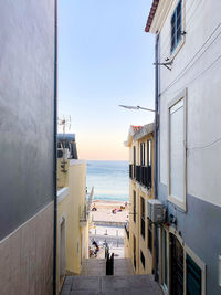 Alley amidst buildings in city against clear sky