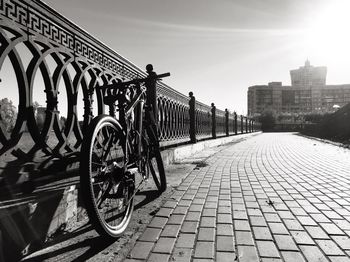 Bicycle on footpath in city against sky