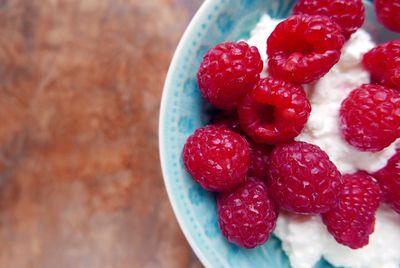 Directly above shot of raspberries with cottage cheese in bowl on table